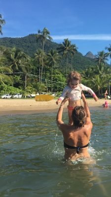 mae brincando com filha no mar